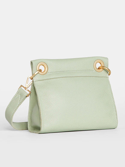 Pastel green Hammitt Los Angeles Tony Small Crossbody Bag in Cypress Sage with a gold-tone shoulder strap attached through large ring loops, against a white background.