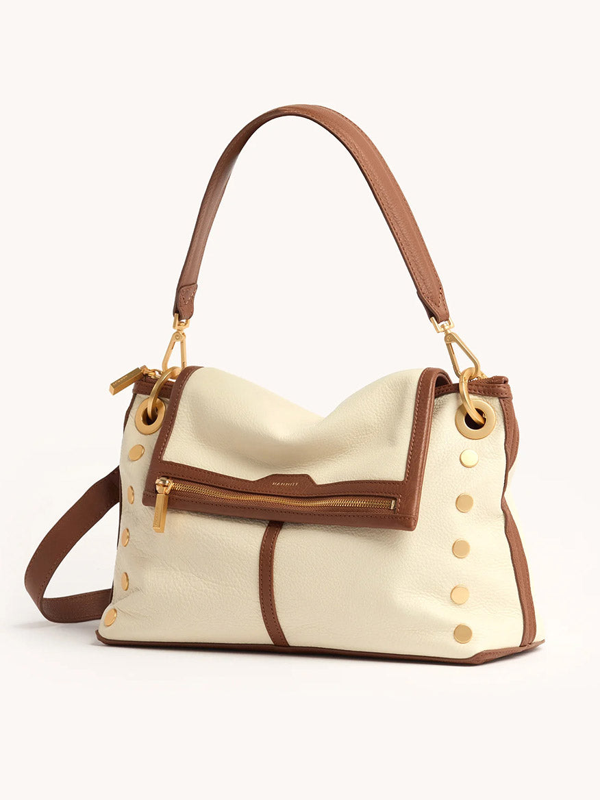 The Hammitt Los Angeles VIP Grand in Courtyard Cream features cream leather, brown trim, gold hardware, side studs, a top handle, and a front zip pocket—combining classic style with the versatility of a convertible crossbody bag.