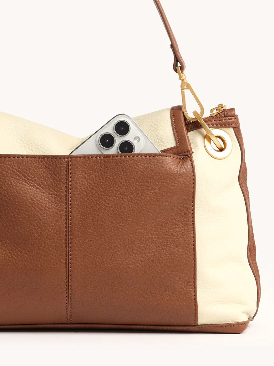 The Hammitt Los Angeles VIP Grand in Courtyard Cream is a brown and cream leather crossbody bag, shown with an iPhone partially visible in the exterior pocket.