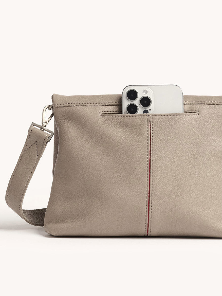 A Hammitt Los Angeles VIP Medium Clutch in Pewter Pebble leather is shown with a smartphone partially tucked into its exterior pocket, set against a plain background.