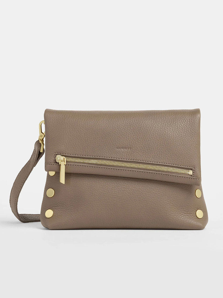 The Hammitt Los Angeles VIP Medium Clutch in Sculpted Taupe leather includes a wrist strap, small zippered pocket, and gold stud accents. It doubles as both a clutch and a crossbody bag, combining elegance with versatility.