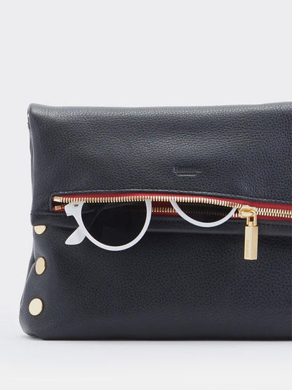 A buttery black Hammitt Los Angeles VIP Medium Clutch in Black with brushed gold button accents and a red zippered compartment partially open, revealing a pair of white-frame glasses inside.