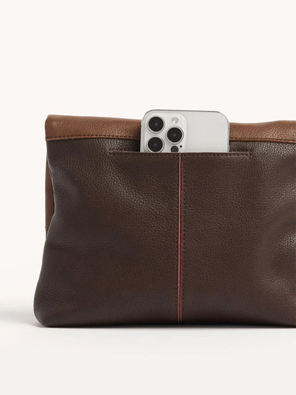 The Hammitt Los Angeles VIP Medium Clutch in Orchestra Brown features an exterior phone pocket that securely holds a smartphone, with the camera lenses partially visible and facing forward.