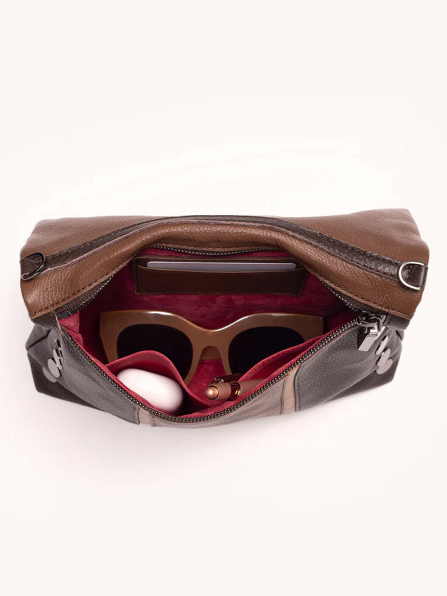 The Hammitt Los Angeles VIP Medium Clutch in Orchestra Brown opens to reveal sunglasses, a lipstick, and a small white item inside, with an exterior phone pocket.