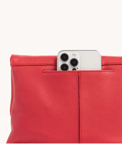 A Hammitt Los Angeles VIP Medium Clutch in poppy red leather reveals a smartphone with three cameras partially visible.