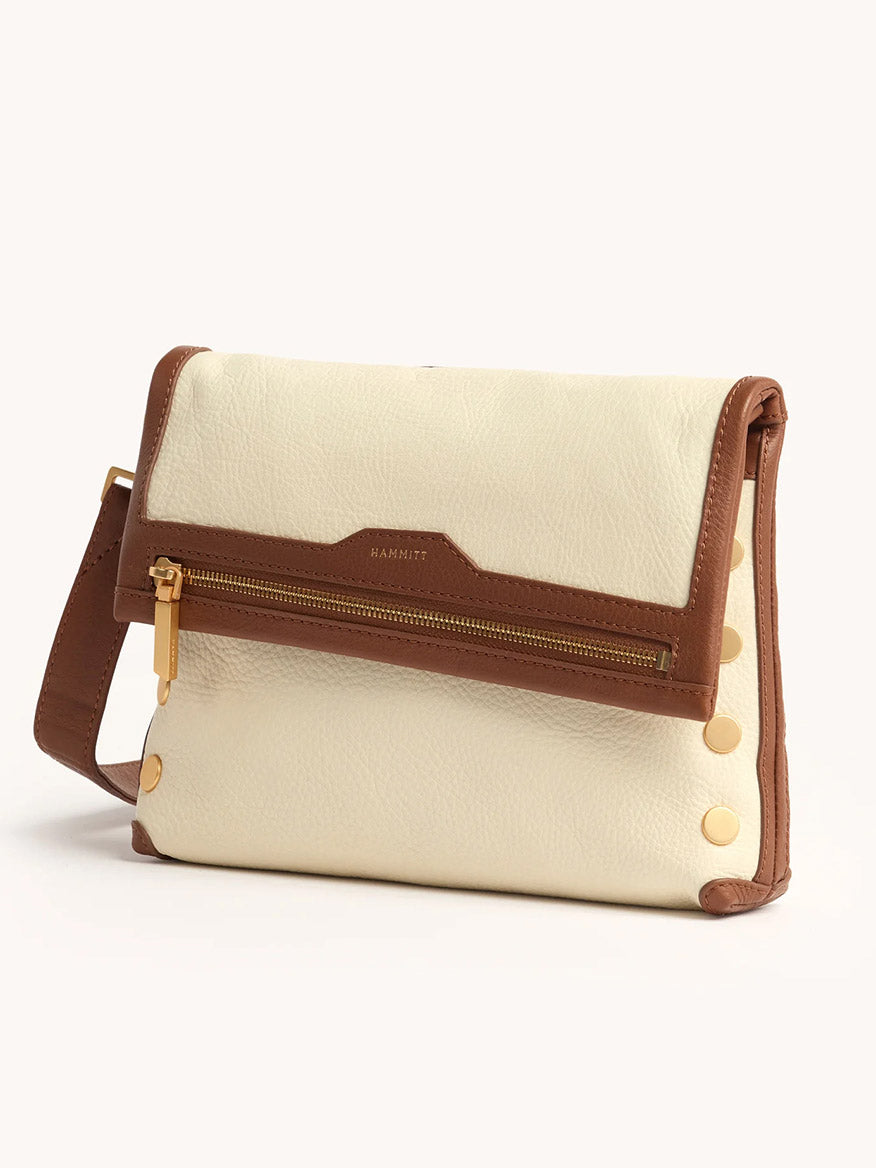 The Hammitt Los Angeles VIP Medium Clutch in Courtyard Cream features cream and brown leather, a front zipper pocket, gold hardware, and gunmetal rivets along the sides for a modern touch.