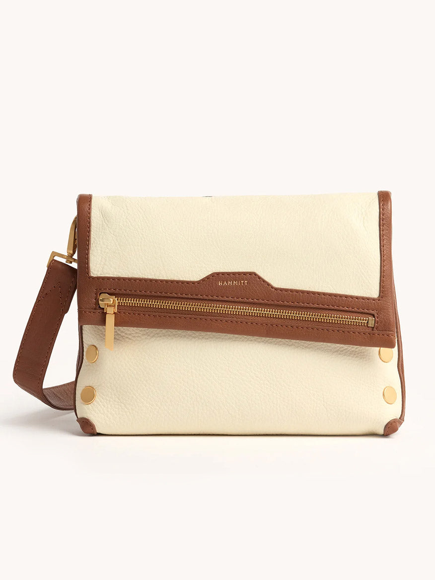 The Hammitt Los Angeles VIP Medium Clutch in Courtyard Cream features a cream and brown design, front zipper pocket, gold hardware, and an adjustable strap, shown against a plain light background.