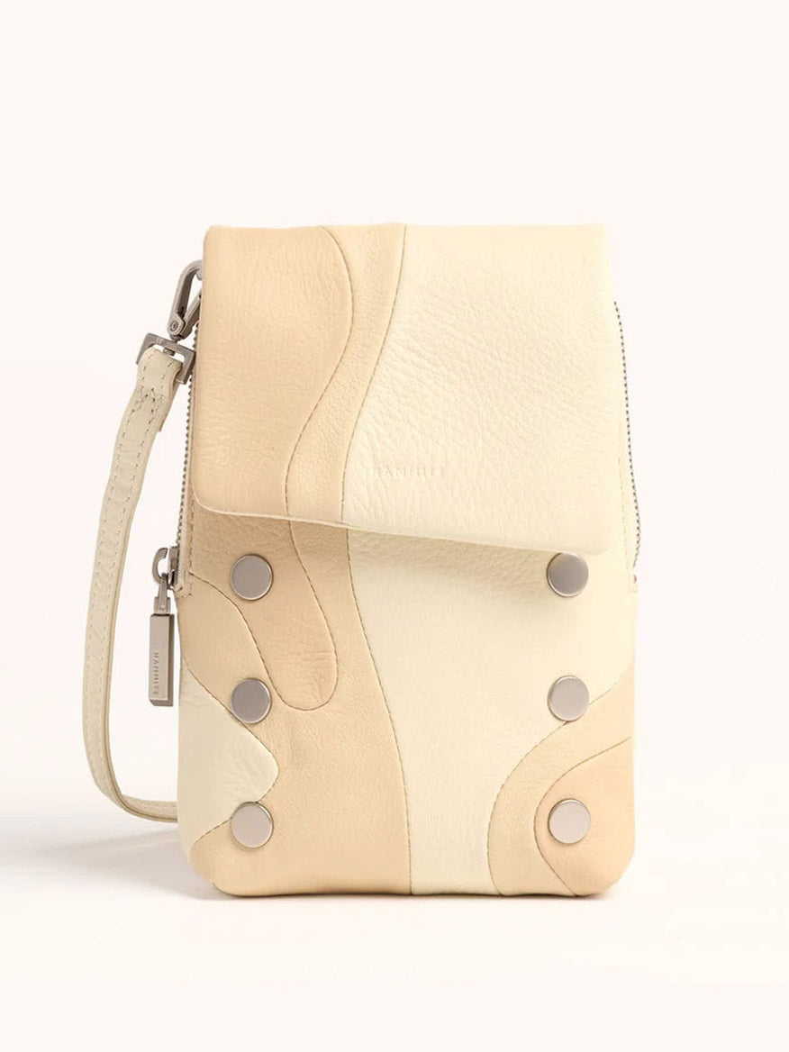 The Hammitt Los Angeles VIP Mobile in Coastal Cream is a compact crossbody bag featuring a patchwork design in beige and cream tones with metal studs and a zippered closure.