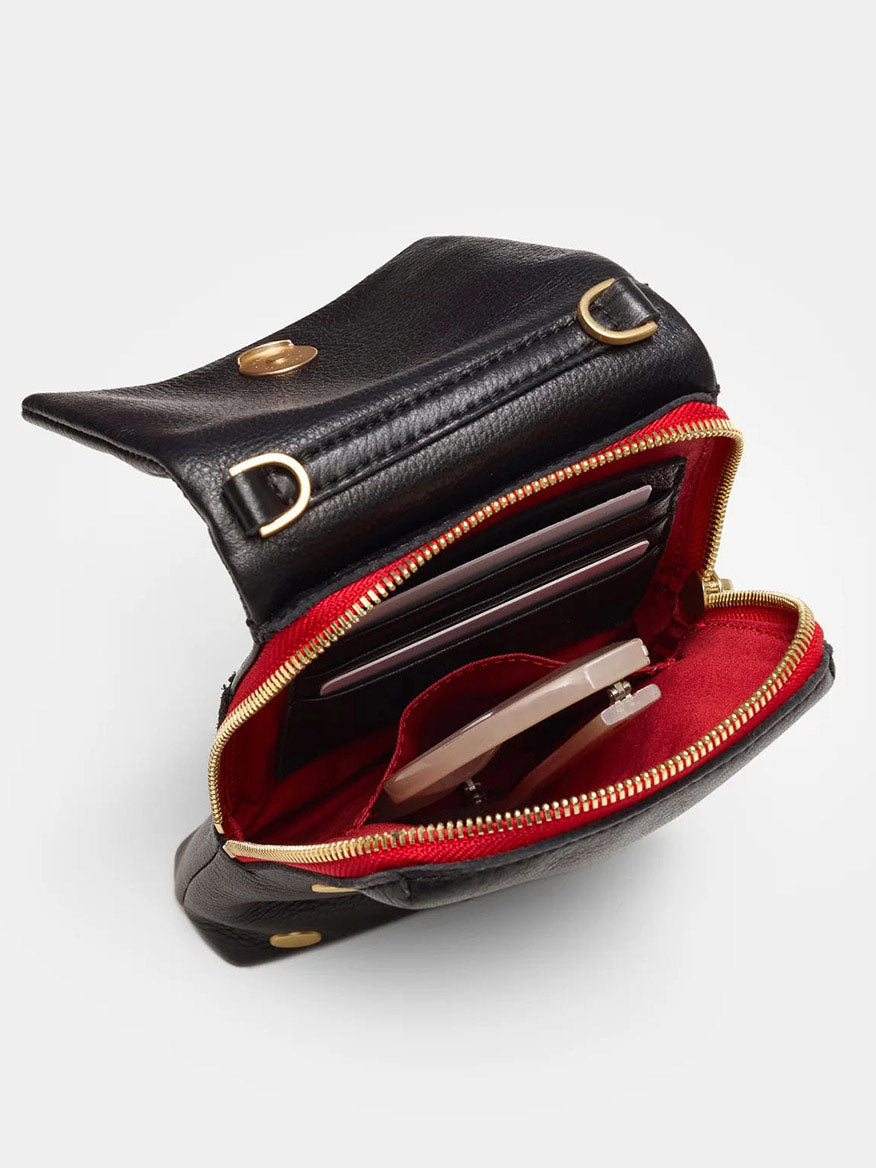 The Hammitt Los Angeles VIP Mobile in Black, Brushed Gold & Red Zip is a black pebbled leather bag with a red interior, featuring compartments for a smartphone, cards, and small items. It includes a detachable strap for versatile crossbody wear.