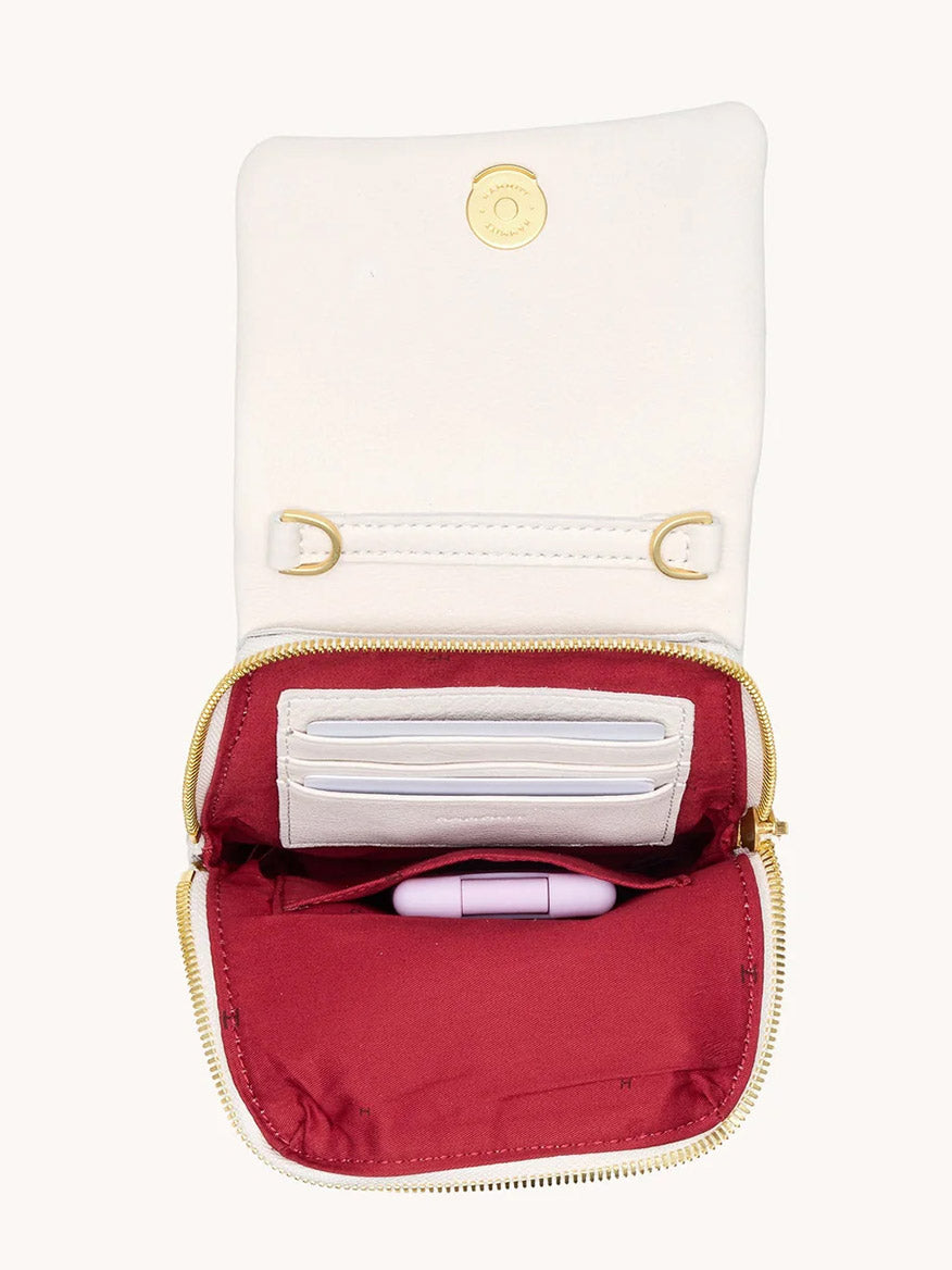 The Hammitt Los Angeles VIP Mobile in Calla Lily White/Brushed Gold features white pebble leather, a gold zipper, snap fastener, card slots, maroon interior, and a pink charm—ideal for keeping essentials organized in your crossbody bag.