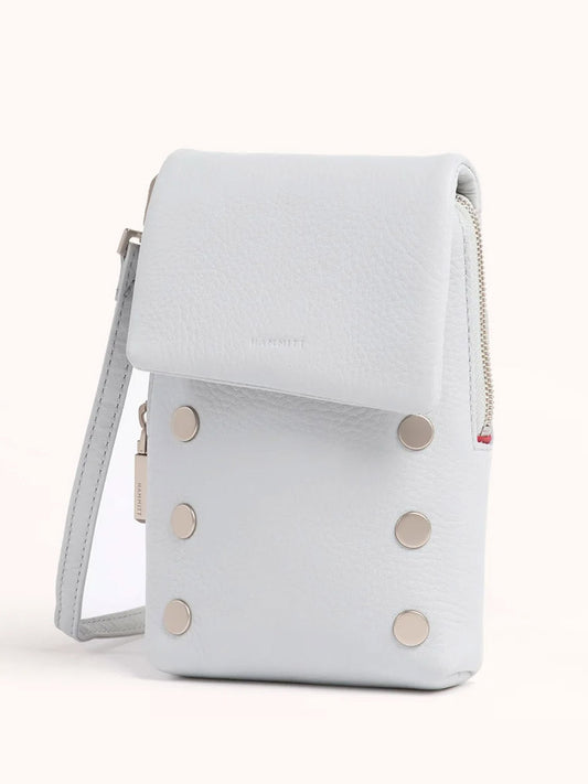 The Hammitt Los Angeles VIP Mobile in Bluebird is a stylish crossbody crafted from pastel pebbled leather, featuring a light gray front flap with silver studs and a top zipper. It includes a convenient wrist strap on the right side for versatile carrying options.