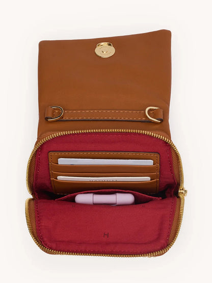 The Hammitt Los Angeles VIP Mobile in Cocoa Raffia/Gold, open to reveal card slots with cards and a lipstick inside its red-lined compartment.