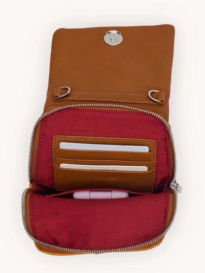 An open Hammitt Los Angeles VIP Mobile in Tailored Tangerine/Silver crossbody wallet displays a red interior, card slots with two cards, and a pocket holding a pink pen.
