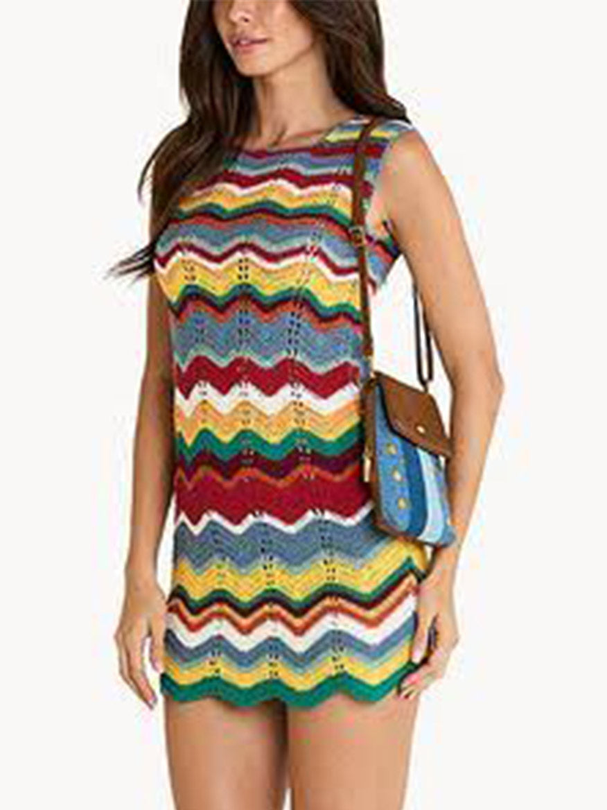 Woman wearing a sleeveless, multicolored zigzag-patterned mini dress and carrying the Hammitt Los Angeles VIP Mobile in Silverlake/Antique Gold crossbody bag with denim leather trim, posed against a plain white background.