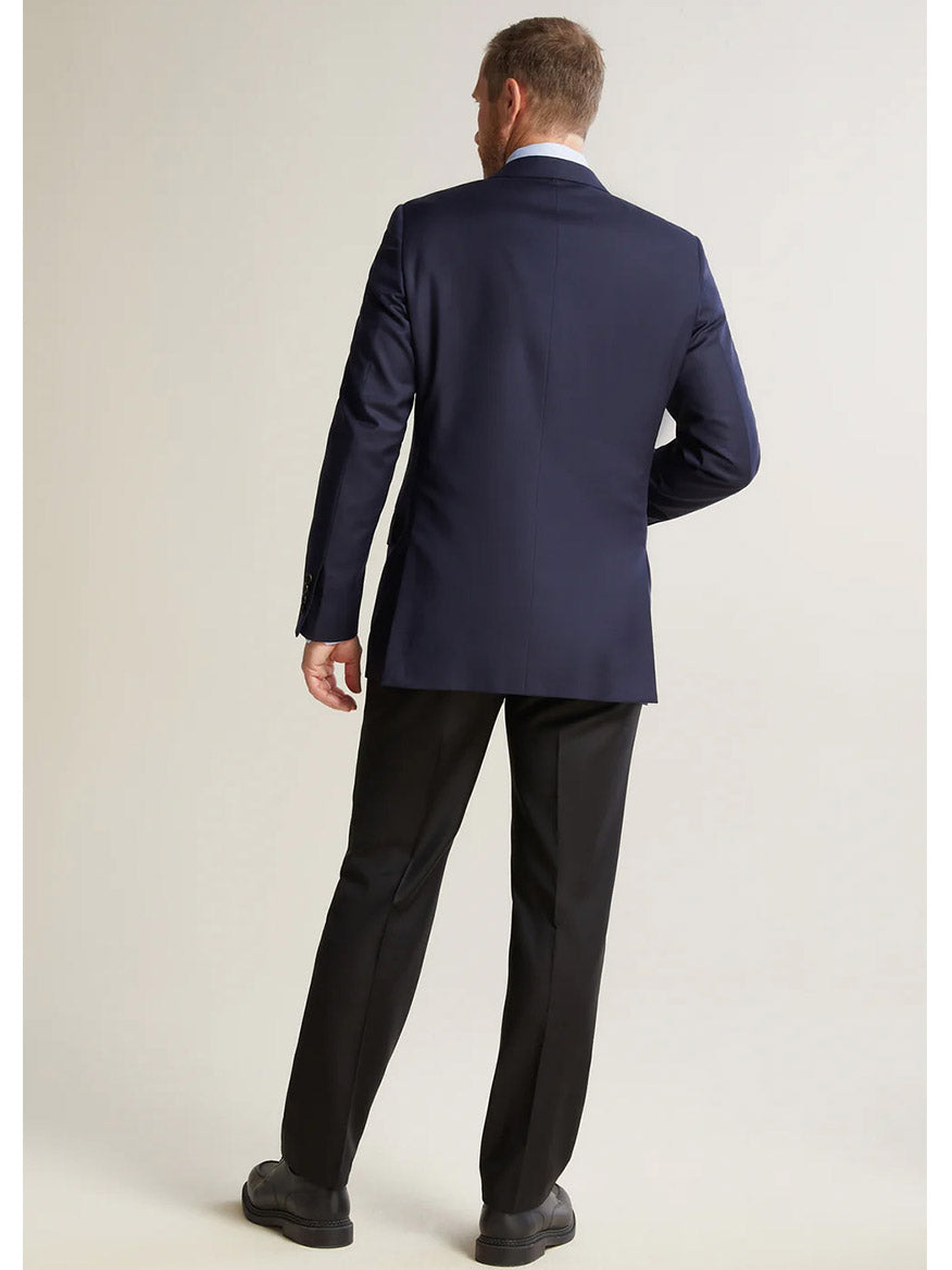 A modern gentleman in a dark suit and black shoes, standing confidently, embodies elegance wearing the Hickey Freeman (Heritage Gold) Navy Traveler Honey Way Blazer crafted from fine wool.