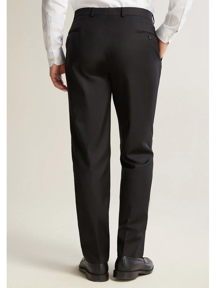 Seen from behind, a person stands on a neutral background wearing the Hickey Freeman (Heritage Gold) Black Infinity Suit, featuring black dress pants crafted from Carlo Barbera mill's exquisite Super 140s Infinity wool.
