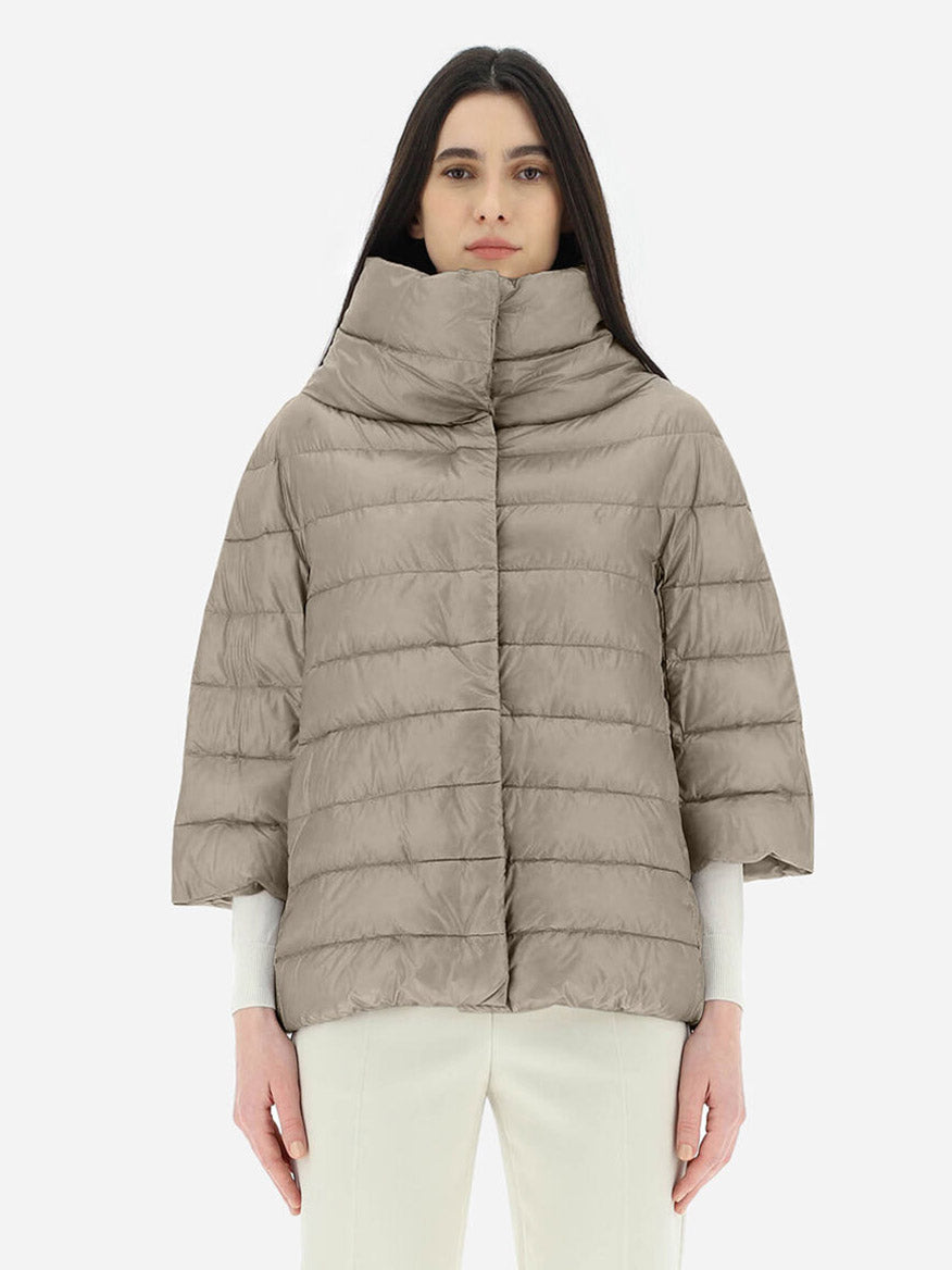 A woman wearing a Herno Aminta 3/4 Sleeve Cocoon Jacket in Taupe filled with ultralight goose down.