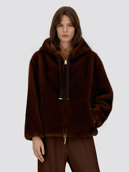 A woman wears the Herno Bomber Jacket With Melange Alternative Mink Fur in chocolate, featuring a hood and drawstrings, paired with matching brown pants against a plain light background.