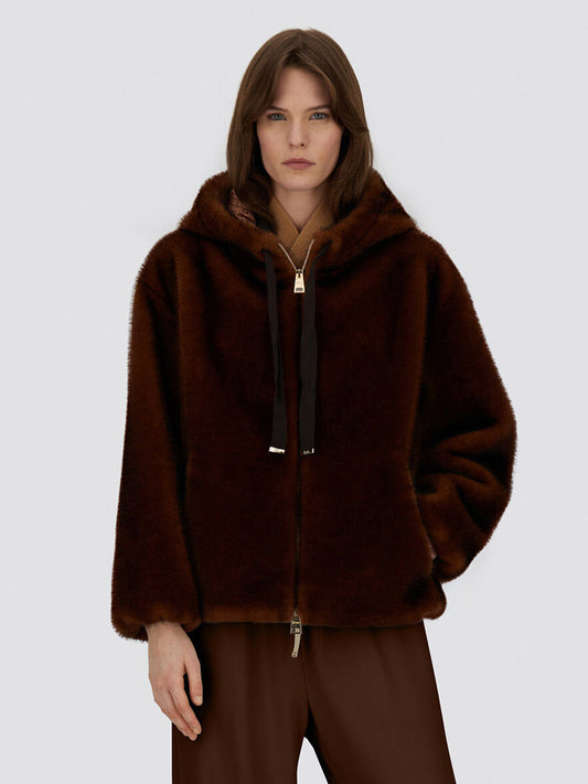 A woman wears the Herno Bomber Jacket With Melange Alternative Mink Fur in chocolate, featuring a hood and drawstrings, paired with matching brown pants against a plain light background.