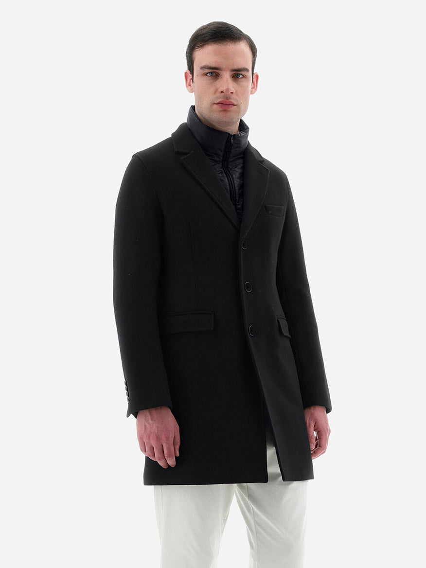 Man in a Herno Diagonal Wool Coat in Black and dark turtleneck, standing against a white background.