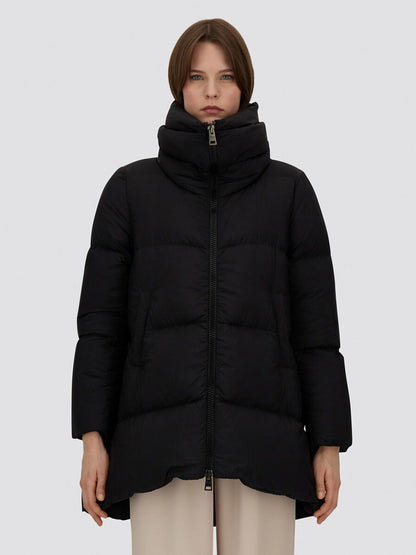 A person stands facing forward wearing the Herno A-Shape Jacket in Ecoage in Black and beige pants against a plain light gray background.