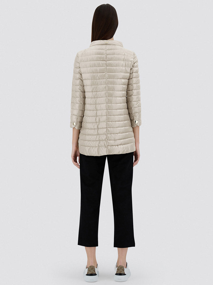 Seen from behind, a person with long hair wears the Herno Rossella A-Shape Jacket in Chantilly, paired with black cropped pants and gray slip-on shoes, set against a plain background.