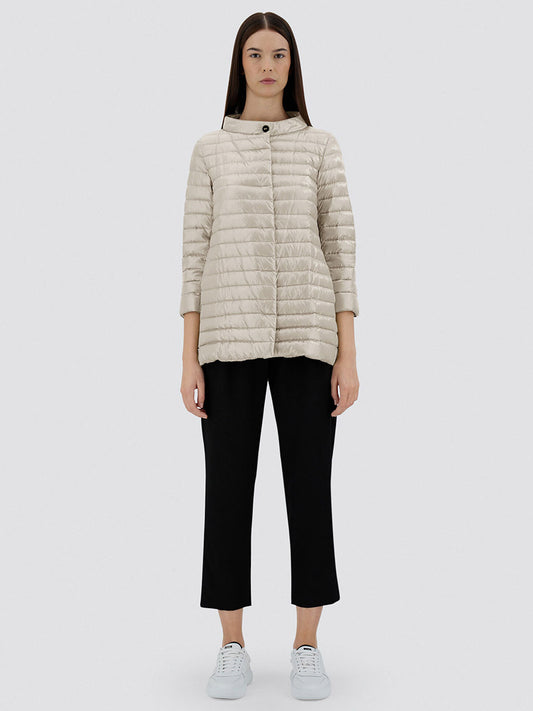 A woman faces forward wearing the Herno Rossella A-Shape Jacket in Chantilly, paired with black cropped pants and white sneakers, set against a plain gray background.