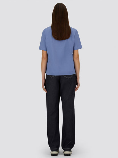 A person stands facing away, wearing the Herno Superfine Cotton Stretch T-Shirt in Light Blue, dark jeans, and sneakers against a plain gray background.