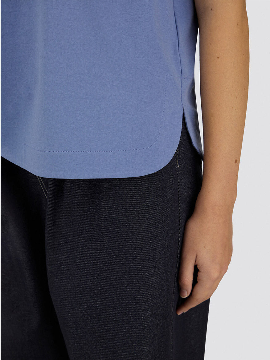 A person is seen from mid-torso to thigh wearing the Herno Superfine Cotton Stretch T-Shirt in Light Blue and dark pants, with their right arm relaxed by their side.