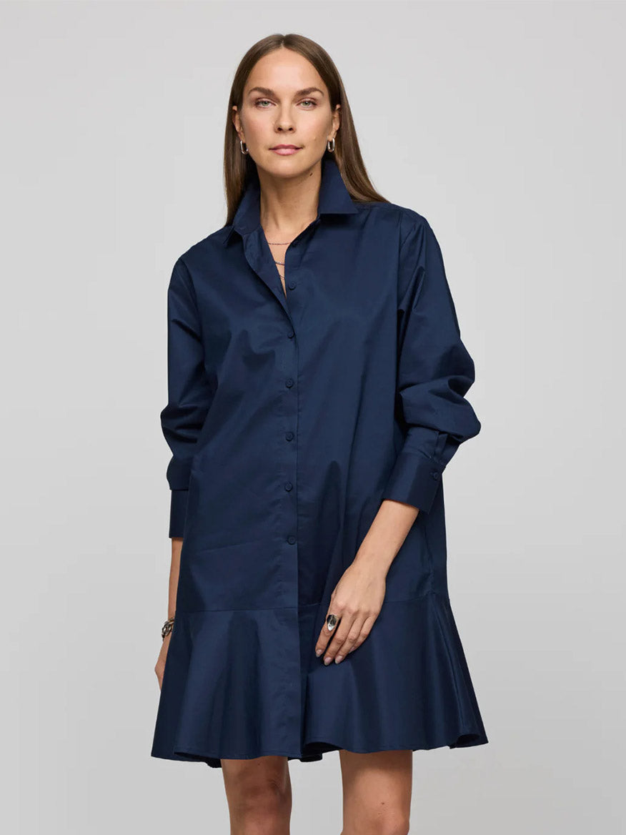 In a sophisticated style, someone wears the Hinson Wu Adeline Long Sleeve Dress in Navy, showcasing its flounce hem. Made from stretch polished cotton, the dress contrasts beautifully against a simple background.