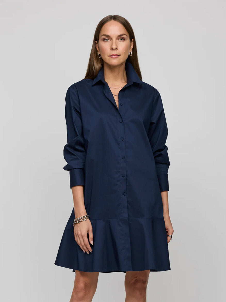 A person wearing a Hinson Wu Adeline Long Sleeve Dress in Navy, featuring a flounce hem, stands against a plain gray background.