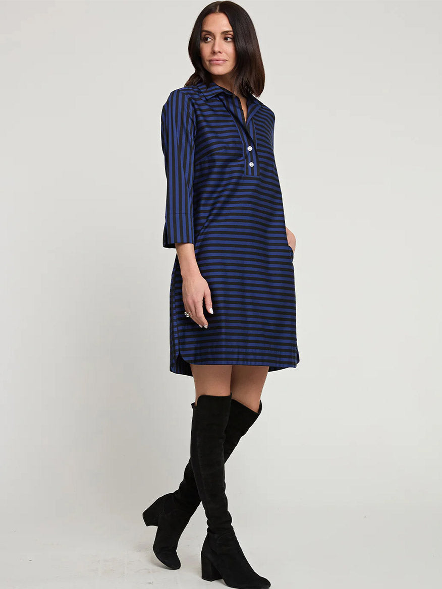 A woman in a stylish Hinson Wu Aileen 3/4 Sleeve Stripe/Gingham Combo Dress in Sapphire/Black, paired with black knee-high boots, stands against a plain background, looking to her right.