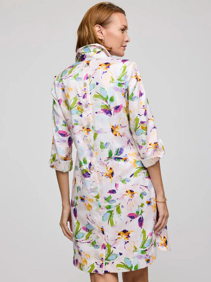 Wearing the Hinson Wu Aileen 3/4 Sleeve Garden Sateen Dress in Garden Multi, a woman faces away. Made from Cotton Blend Satin, it features a colorful floral pattern, rolled-up sleeves, back buttons, and is machine washable.
