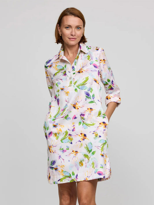 A woman wears the Hinson Wu Aileen 3/4 Sleeve Garden Sateen Dress in Garden Multi, a cotton-blend satin dress with a white base and colorful floral print, standing against a plain light gray background.