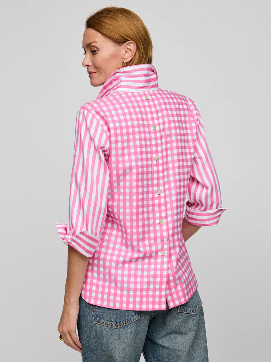 A person in the Hinson Wu Aileen 3/4 Sleeve Stripe/Check Combo Top in Guava/White, featuring a classic pink and white checkered design with back buttons, is paired with denim jeans and faces away.