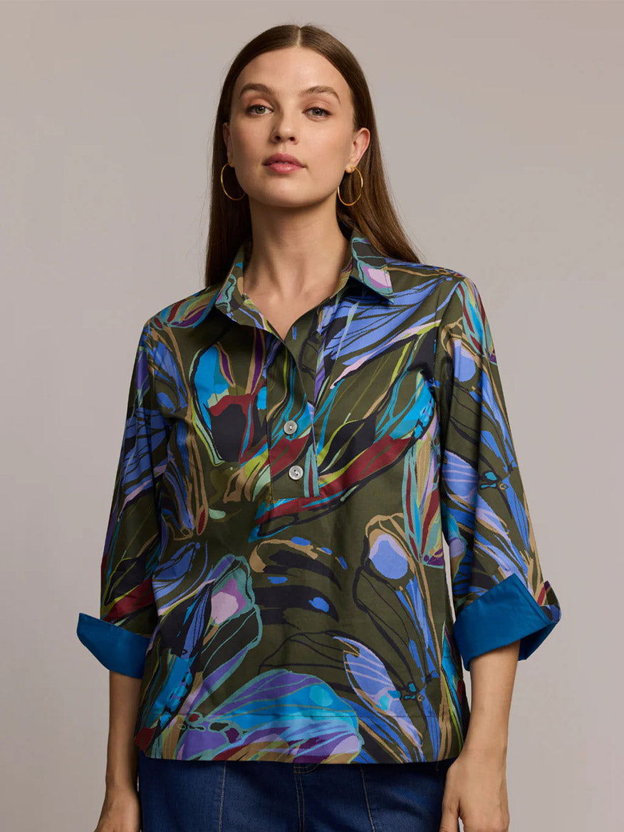 A woman wears the Hinson Wu Aileen 3/4 Sleeve Abstract Camo Shirt with sapphire tones, featuring a premium cotton blend and bold blue-green pattern, standing against a neutral background.