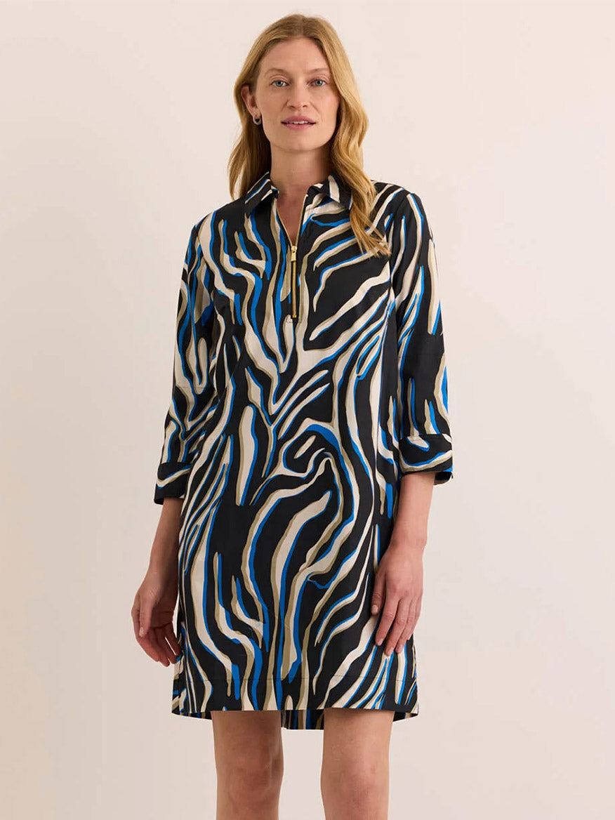 A woman wearing the Hinson Wu Alessa 3/4 Sleeve Abstract Zebra Dress—crafted from a premium cotton blend and showcasing bold black, white, and blue abstract zebra prints—stands against a plain light background.