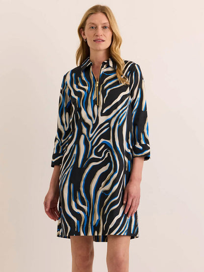 A woman wearing the Hinson Wu Alessa 3/4 Sleeve Abstract Zebra Dress—crafted from a premium cotton blend and showcasing bold black, white, and blue abstract zebra prints—stands against a plain light background.