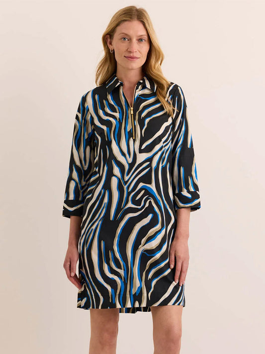 A woman stands against a plain background wearing the Hinson Wu Alessa 3/4 Sleeve Abstract Zebra Dress, a knee-length design made from a premium cotton blend with striking black, white, and blue zebra-inspired patterns and a short zip at the neckline.