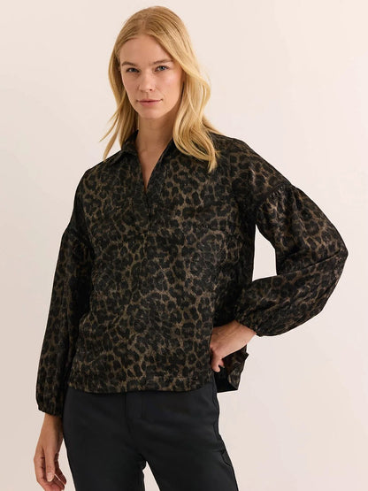 A person wearing the Hinson Wu Arianna Long Sleeve Animal Print Top paired with black pants stands against a plain, light background.