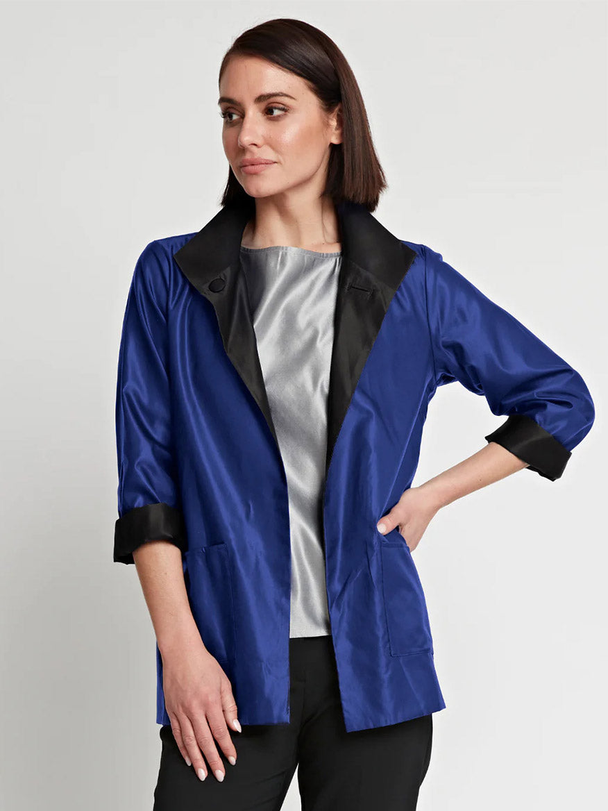 A woman wearing a Hinson Wu Constance Reversible Long Sleeve Silk Satin Jacket in Royal/Black made of silk blend satin and black pants.