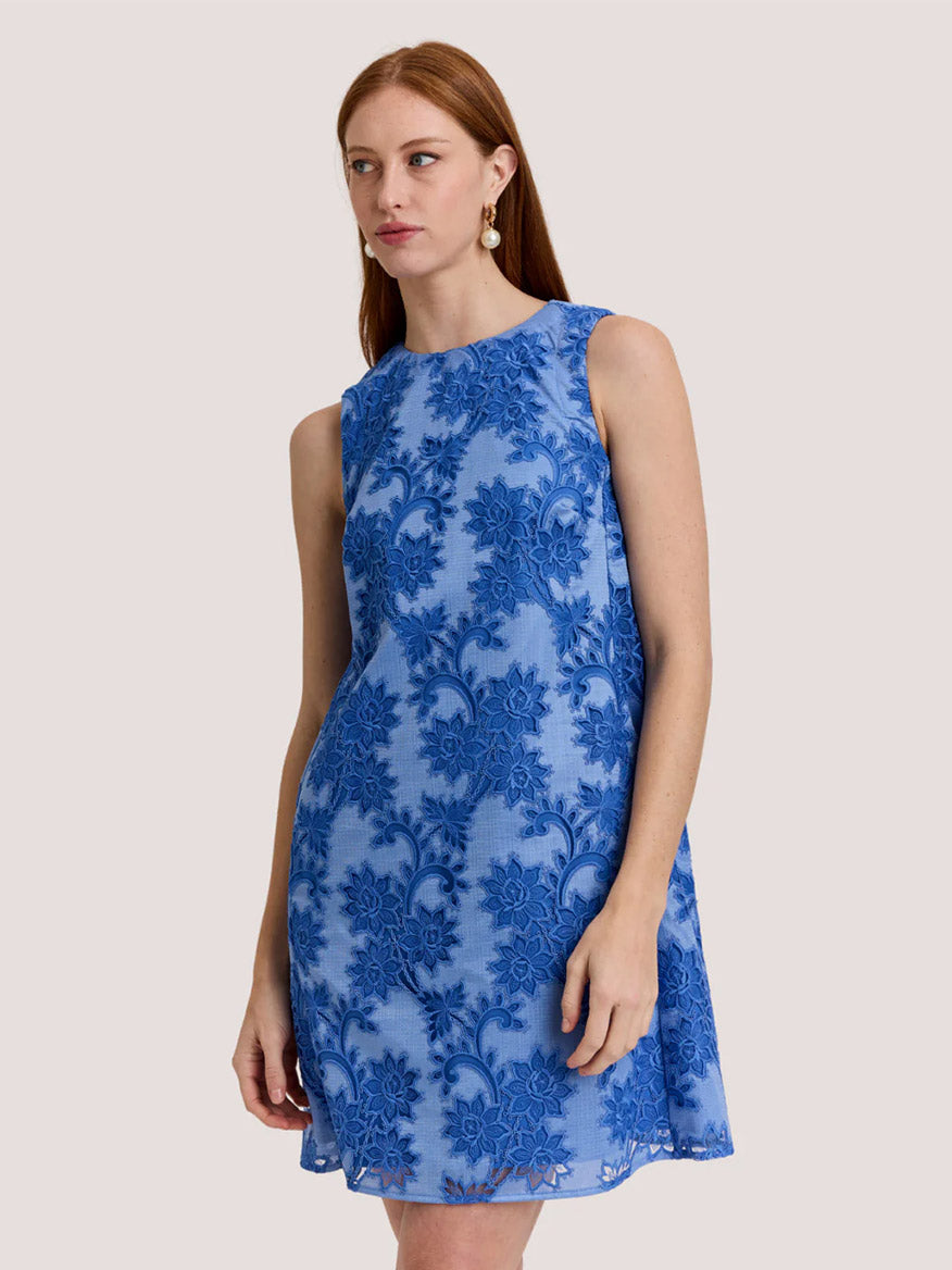 A woman wears the Hinson Wu Courtney Sleeveless Floral Motif Lace Dress in Lake Blue, standing against a plain light background.