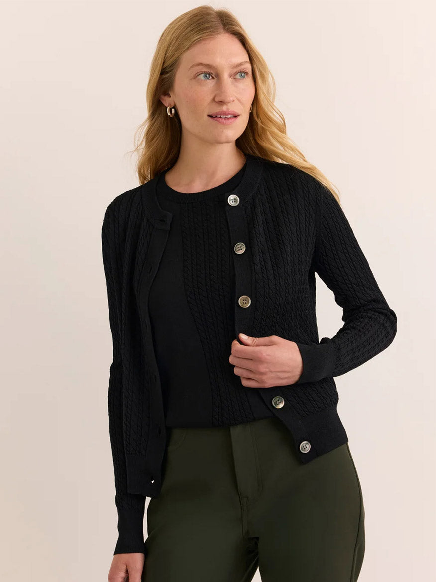 A woman wears the Hinson Wu Edith Cardigan & Ashley Sleeveless Turtleneck Set in Black, paired with olive green pants against a neutral background—an effortlessly chic ensemble reminiscent of an elegant dress.