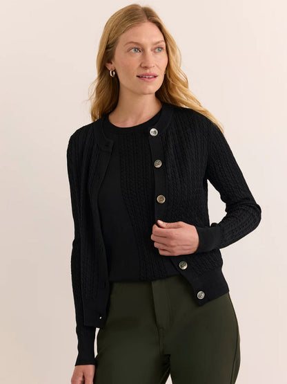 A woman wears the Hinson Wu Edith Cardigan & Ashley Sleeveless Turtleneck Set in Black, paired with olive green pants against a neutral background—an effortlessly chic ensemble reminiscent of an elegant dress.