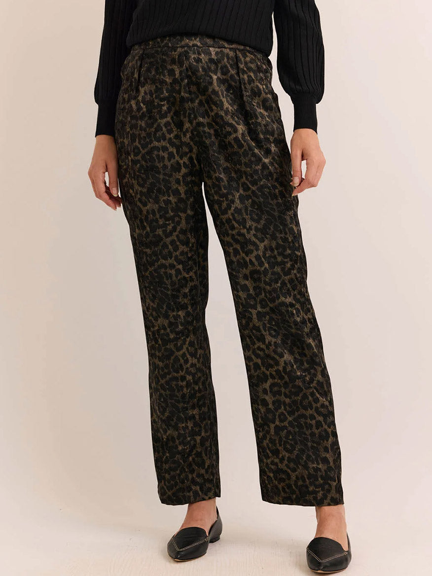 A person wearing the Hinson Wu Hostess Animal Print Pant in Animal Print, paired with a black ribbed sweater and black flat shoes, stands against a light background.