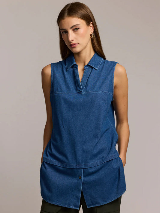 A woman with straight brown hair wears the Hinson Wu Lea Sleeveless Knit Denim Foundation Layer in Medium Wash, styled with a collar and split neckline, standing with her hands in her pockets against a plain background.