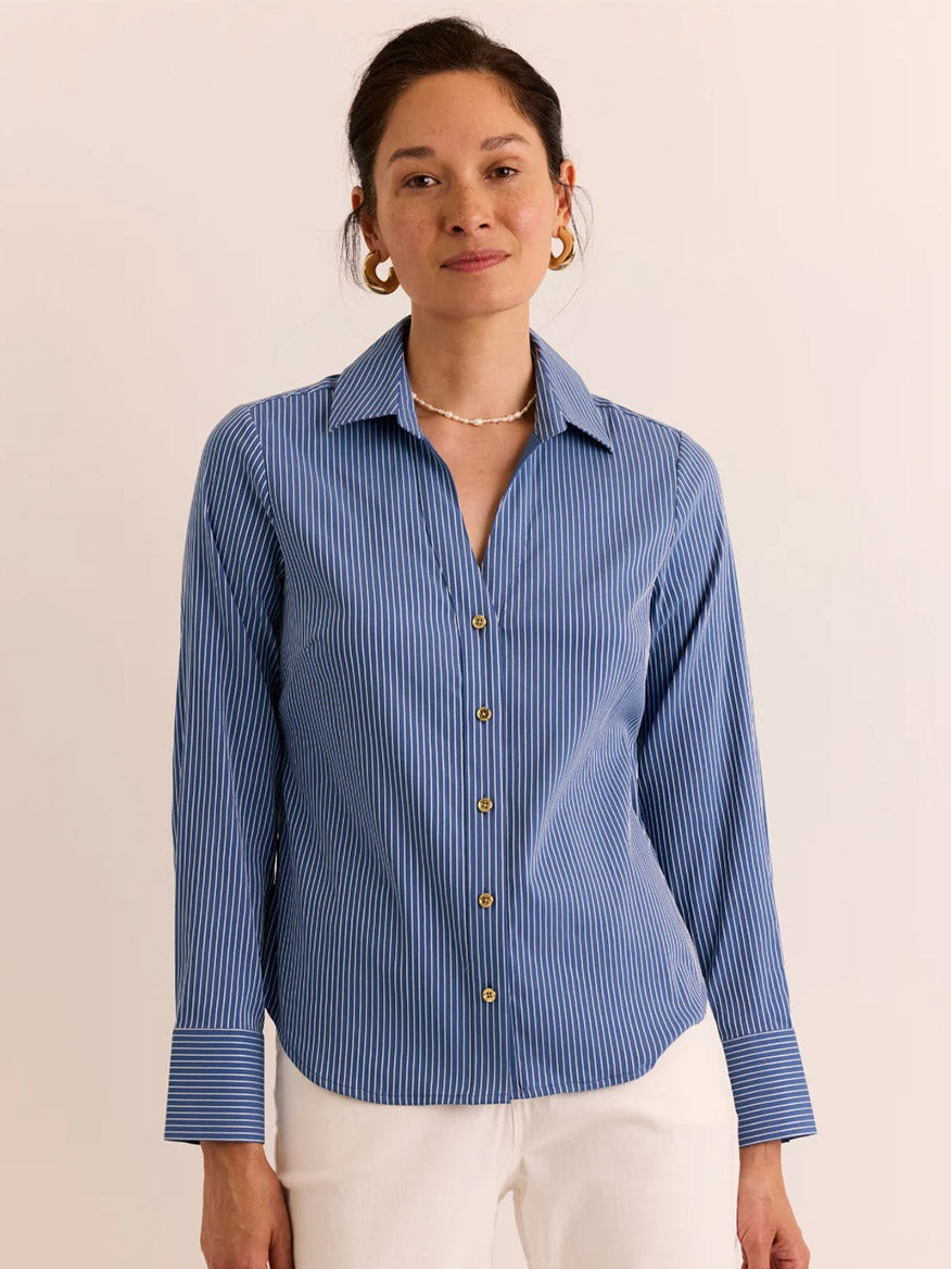 A woman stands against a neutral background, wearing the Hinson Wu Lindsey Long Sleeve Ribbon Stripe Shirt in Blue/White Stripe and white pants.
