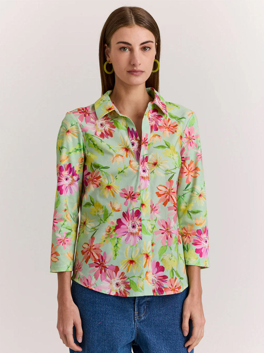 A woman models the Hinson Wu Lizette 3/4 Sleeve Green Floral Print Top, a premium cotton knit shirt with a bright floral pattern, paired with blue jeans against a neutral background for an effortlessly stylish look.