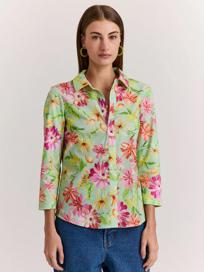 A woman models the Hinson Wu Lizette 3/4 Sleeve Green Floral Print Top, a premium cotton knit shirt with a bright floral pattern, paired with blue jeans against a neutral background for an effortlessly stylish look.