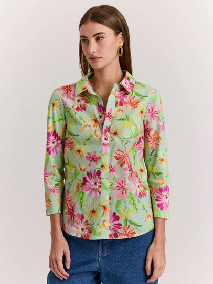 A woman wears the Hinson Wu Lizette 3/4 Sleeve Green Floral Print Top, featuring a light green floral pattern and premium cotton knit, paired with blue jeans.
